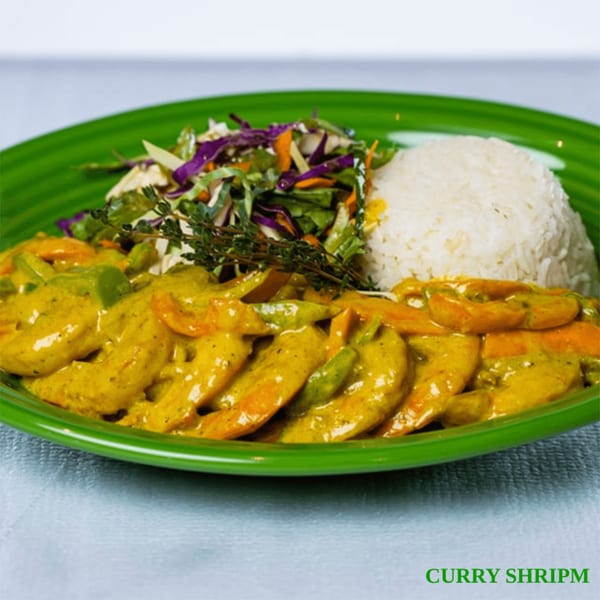 Curry shrimp with white rice and a side salad on a vibrant green plate.