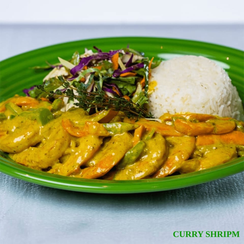 Curry shrimp with white rice and a side salad on a vibrant green plate.