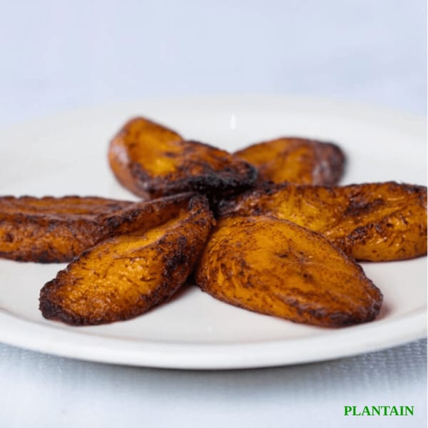 A white plate holds several golden-brown, fried plantain slices, a Jamaican cuisine staple.